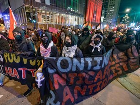 Protesters walk holding up a banner