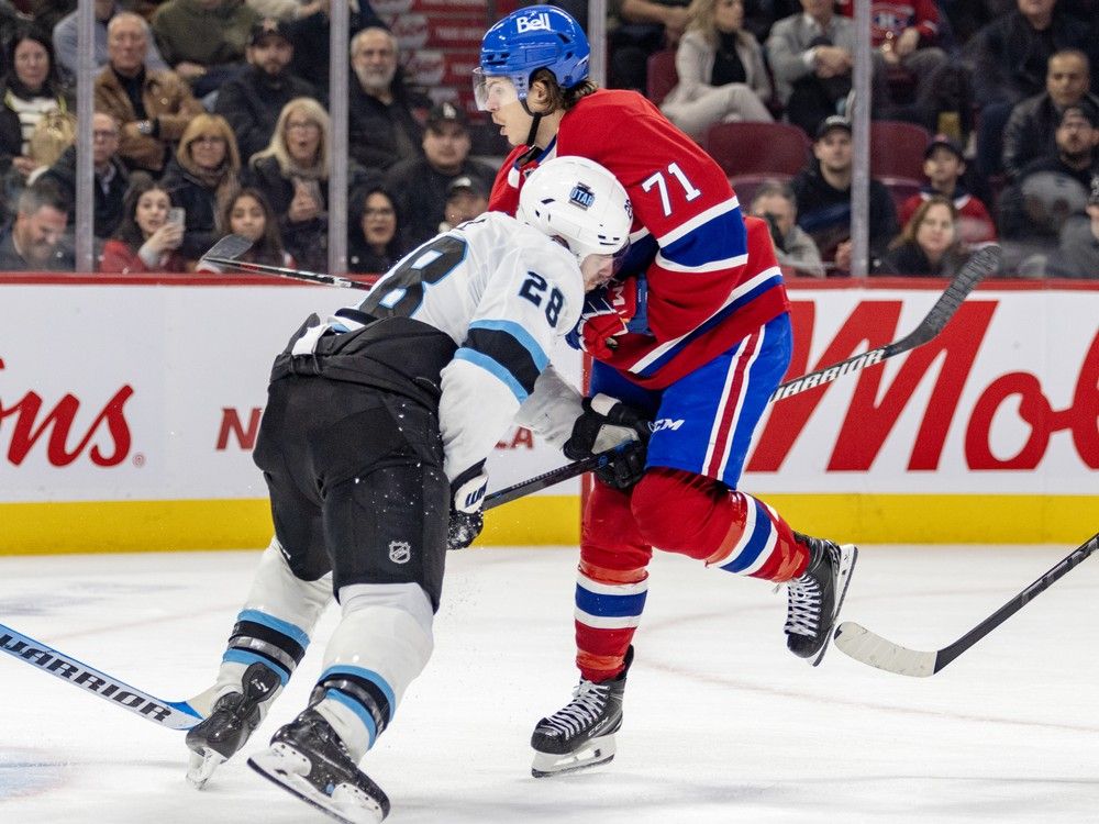 Utah's Ian Cole has his stick through Canadiens player Jake Evans's legs while his head is buried in Evans's chest