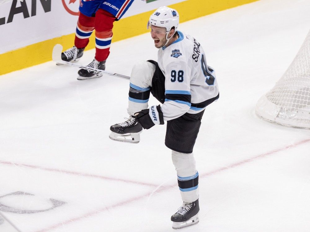 Utah's Mikhail Sergachev lifts up his leg and cheers on the ice