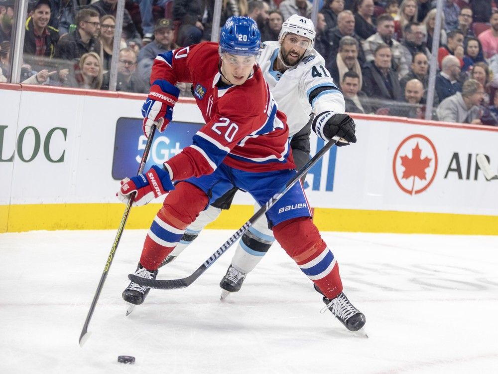 Montreal Canadiens' Juraj Slafkovsky skates with the puck while a Utah player tries to reach his stick around him from behind