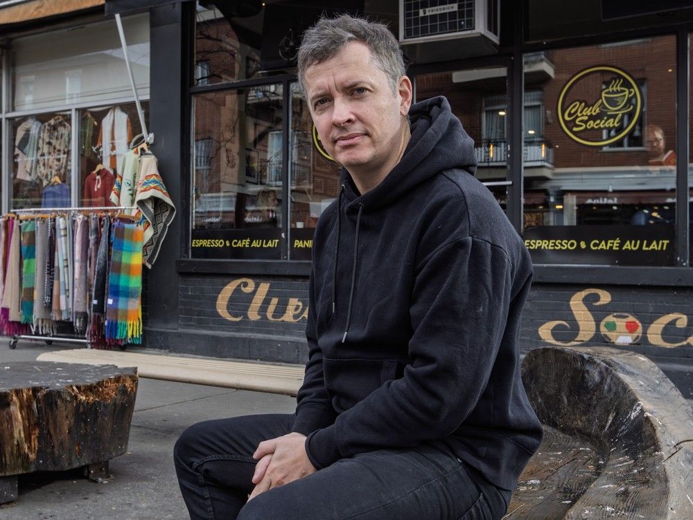 a man sits on a bench outside a café.