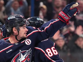 Sean Monahan raises his arm in the air while gathered with Blue Jackets players