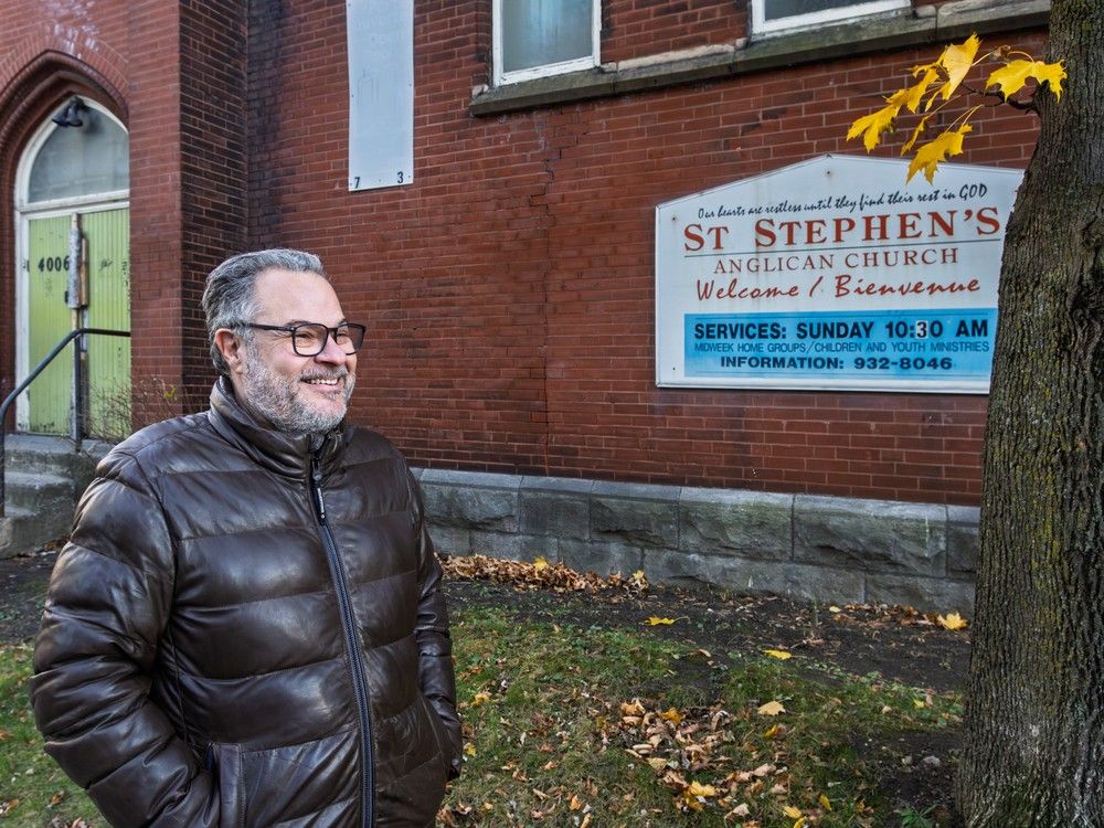 a man smiles as he stands outside a church building.
