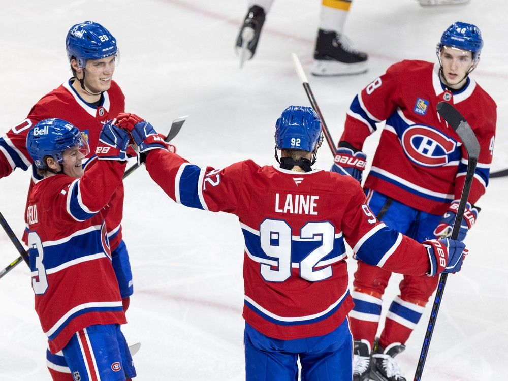 Four Canadiens players skate toward each other on the ice with arms extended