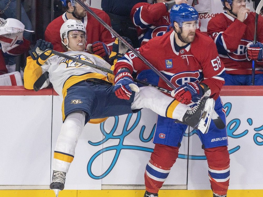 Nashville Predators' Zachary L'Heureux falls backward into the Canadiens bench with Canadiens' David Savard next to him