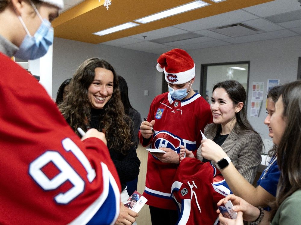 Three women stand smiling with two Canadiens players
