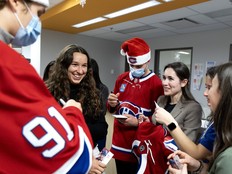 Three women stand smiling with two Canadiens players