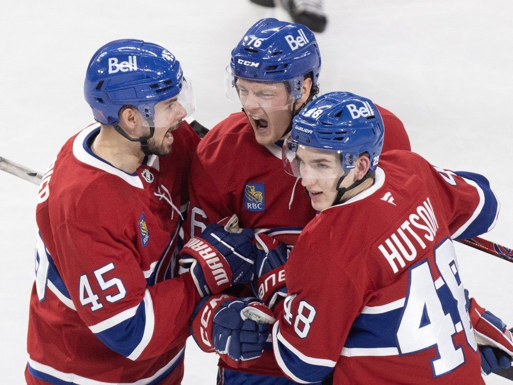 Three hockey players celebrate a goal.