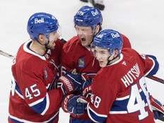 Three hockey players celebrate a goal.