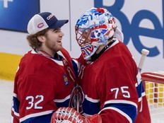 Two hockey goaltender teammates hug after a game.