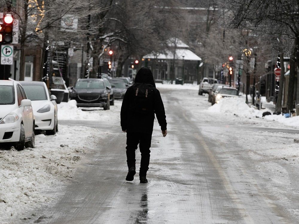 A person walks down the middle of an icy city street.