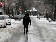 A person walks down the middle of an icy city street.