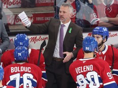Hockey coach directs players while behind the bench.