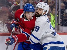 Leafs' Benoit-Olivier Groulx pins Canadiens' Lane Hutson to the boards during second period Tuesday night at the Bell Centre.