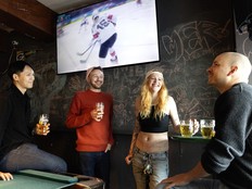 Regulars at Champs bar with hockey on a big TV screen behind them.