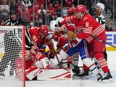 Hockey players from both sides get into a scrum in front of the net.