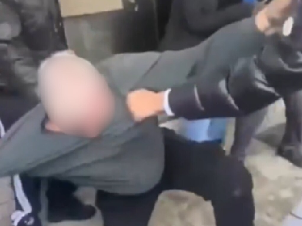 A convenience store supervisor is pushed to the ground outside a high school.