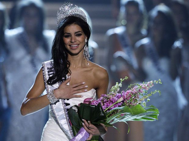 Miss USA, Rima Fakih, wearing jersey, holding pink bat and blue