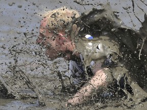 A participant of the "Wattoluempiade" (Mud Olympics) falls into the mud as he competes for the ball during a soccer match.