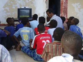People sit around a television set to watch the opening game of the 2010 World Cup in Mogadishu.