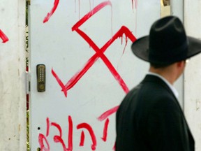 A Jewish man looks at anti-semitic graffiti which was sprayed on the gate of a synagogue.