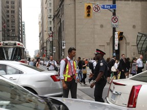 Rishi Ghuldu, a pedestrian, speaks to a Toronto police officer while directing traffic during a power outage in Toronto on July 5, 2010.