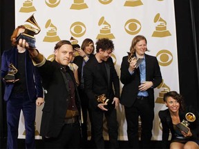 Arcade Fire's Win Butler holds up an Album of the Year award for the album The Suburbs as he poses along with the rest of the band.