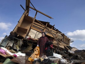 KESENNUMA, JAPAN - MARCH 18:  Aiko Musashi is stunned as she looks at her neighbour's house while collecting personal belongings at her destroyed home on March 18, 2011 in Kesennuma, Japan. Thousands have been killed as a result of the 9.0 earthquake and consequent tsunami that struck the northeast coast of Japan six days ago. A potential humanitarian crisis looms as nearly half a million people who have been displaced by the disaster continue to suffer a shortage of food and fuel as freezing weather conditions set in.  (Photo by Paula Bronstein/Getty Images)