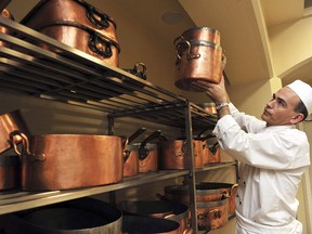 Buckingham Palace head of kitchens, Royal Chef Mark Flanagan, lifts a copper pot from a rack at Buckingham Palace in London March 25, 2011. Staff at Buckingham Palace have lifted the lid on preparations for Prince William's, giving an insight into what guests can expect and the amount of work they have put in to make the event a success.