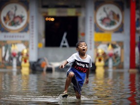 A boy plays in the water outside a flooded temple in Chinatown in central Bangkok October 31, 2011. Thailand's worst floods in half a century have killed nearly 400 people since mid-July, damaged millions of tonnes of rice and forced a series of industrial estates to close. REUTERS/Damir Sagolj (THAILAND - Tags: ENVIRONMENT DISASTER RELIGION)