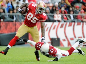 Vernon Davis, left, of the San Francisco 49ers runs through the tackle of Michael Adams of the Arizona Cardinals on Sunday.