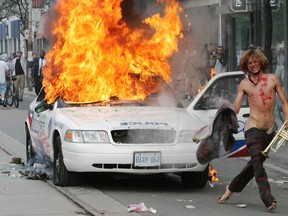 TORONTO, ONTARIO: JUNE 26, 2010 - A man with a trumpet takes his shirt off the hood of a burning cop car on Queen Street West during the G20 Summit in Toronto, Saturday, June 26, 2010. 

(Tyler Anderson/National Post)

(For National)