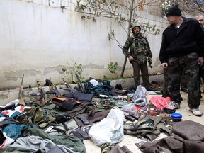 A Syrian soldier displays weapons seized from what officials say were gunmen, during the tour of Arab monitors in Damascus countryside Harasta January 26, 2012. Syrian authorities are holding ceasefire talks with rebels who have seized some areas near Damascus, a local official said on Thursday, in a sign that a 10-month-old revolt against President Bashar al-Assad has crept close to the capital