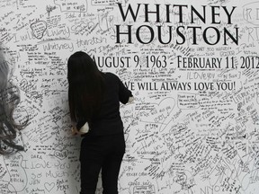 A Filipino fan writes a message on a tribute wall for the late American singer-actress Whitney Houston that is displayed inside a mall in Manila February 15, 2012. Houston was found underwater in a bathtub in a Beverly Hills hotel on Saturday, according to police who have declined to speculate on the cause of her death at age 48. REUTERS/Romeo Ranoco (PHILIPPINES - Tags: ENTERTAINMENT SOCIETY OBITUARY)