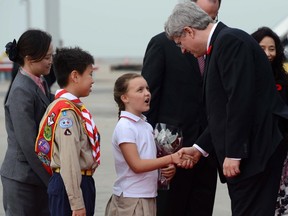 Prime Minister Stephen Harper shakes hands with Harper Jones as Marvin Wong, left, waits to greet him as they arrive in Hong Kong on Sunday.