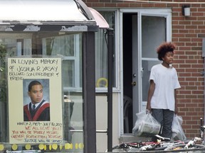 A young man walks from his home's backyard door with a makeshift memorial in a bus shelter (left) for those shot and killed at the Danzig Street block party in July. (Peter J. Thompson / National Post files)