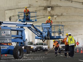 City workers chip away loose chunks of concrete from the Gardiner Expressway above on Lakeshore Boulevard near Yonge Street. / Aaron Lynett / National Post