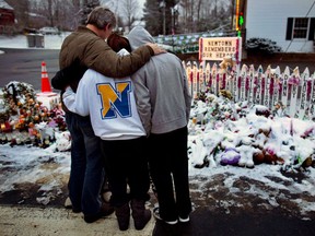 Members of the Rutter family of Sandy Hook, Conn., embrace early Christmas morning as they stand near memorials by the Sandy Hook firehouse in Newtown, Conn., on Tuesday, Dec. 25, 2012.