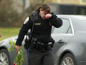A police officer wipes her eys as she removes flowers from a busy intersection December 16, 2012 in Newtown, Connecticut, which they said they were afraid the memorial, left for the Sandy Hook Elementary school victims, may cause a traffic hazard. The people of Newtown, soon to be joined by President Barack Obama, poured into churches Sunday to pray for the 20 children and seven adults slaughtered in one of the worst ever US shooting massacres. The small Connecticut town led the nation in mourning 48 hours after Adam Lanza burst into Sandy Hook Elementary School and murdered two roomfuls of six- and seven-year-old children, the school principal and five other female staff. From early Sunday churches filled and the town Christmas tree became an impromptu place of remembrance, with people pausing every few minutes to pray and cross themselves under a light snowfall.   AFP PHOTO/DON EMMERTDON EMMERT/AFP/Getty Images