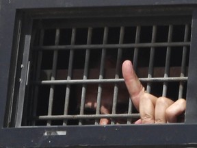 In this Oct. 16, 2011 file photo, a Palestinian prisoner peeks from an Israeli Prison Service bus in Mitzpe Ramon, Israel.