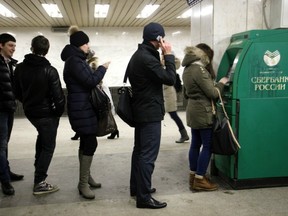 Customer line up to withdraw cash from an automated teller machine (ATM) operated by OAO Sberbank in Moscow, Russia, on Friday, March 22, 2013. Russian lenders with Cypriot units include OAO Sberbank and OAO Gazprombank, both state-controlled, Otkritie Capital, part-owned by VTB, as well as Aton Capital, UralSib Financial Corp. OAO Promsvyazbank and BCS Financial Group. Photographer: Alexander Zemlianichenko Jr/Bloomberg