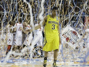 Michigan guard Trey Burke (3) walks off the court as Louisville celebrate their win during the second half of the NCAA Final Four tournament college basketball championship game Monday, April 8, 2013, in Atlanta. Louisville won 82-76. (AP Photo/Charlie Neibergall)