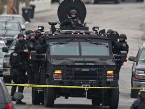 Police in tactical gear arrive on an armored police vehicle as they surround an apartment building while looking for a suspect in the Boston Marathon bombings in Watertown, Mass., Friday, April 19, 2013. The bombs that blew up seconds apart near the finish line of the Boston Marathon left the streets spattered with blood and glass, and gaping questions of who chose to attack and why. (AP Photo/Charles Krupa)