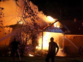 A person looks on as emergency workers fight a house fire after a near by fertilizer plant exploded in West, Texas.