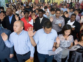 New Canadian citizens take the citizenship oath during the Citizenship and Immigration Ceremony.