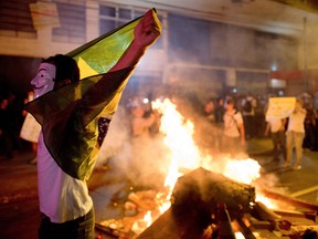 A demonstrator holds a flag late on June 19, 2013 during clashes in the center of Niteroi, 10 kms from Rio de Janeiro. Protesters battled police late on June 19, even after Brazil's two biggest cities rolled back the transit fare hikes that triggered two weeks of nationwide protests.  The fare rollback in Sao Paulo and Rio de Janeiro marked a major victory for the protests, which are the biggest Brazil has seen in two decades.   AFP PHOTO / CHRISTOPHE SIMONCHRISTOPHE SIMON/AFP/Getty Images