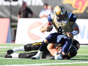Winnipeg Blue Bombers quarterback Buck Pierce, left, is sacked by Hamilton Tiger-Cats' Brian Bulcke during first half CFL action in Guelph, Ont., Saturday, July 13, 2013.