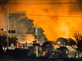 Smoke and fire rises over train cars as firefighters inspect the area after a train carrying crude oil derailed and exploded in the town of Lac-Mégantic on July 6, 2013.