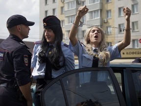A Russian gay rights activist wears handcuffs while he and others, dressed as female police officers, protest against a new gay propaganda law, in Moscow, Russia.