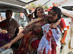 A Pakistani man carries an injured Christian woman on her arrival at the hospital after two suicide bomb attacks on a Church in Peshawar on September 22, 2013. Two suicide bombers killed at least 53 people and wounded more than 100 in an attack on a church service in the restive northwestern Pakistani city of Peshawar, officials said.